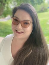 Alanna Burke Headshot. Smiling Brunette with glasses. 